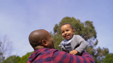 Afroamerikanischer-Vater-Wirft-Sohn-In-Die-Luft,-Kind-Lacht